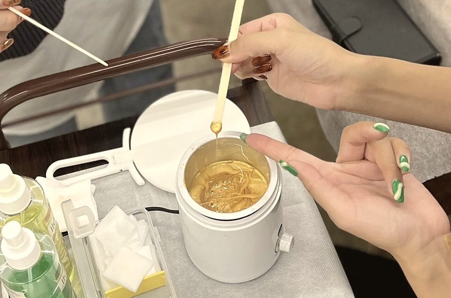 ウォーマーで溶かしたワックスをすくう様子